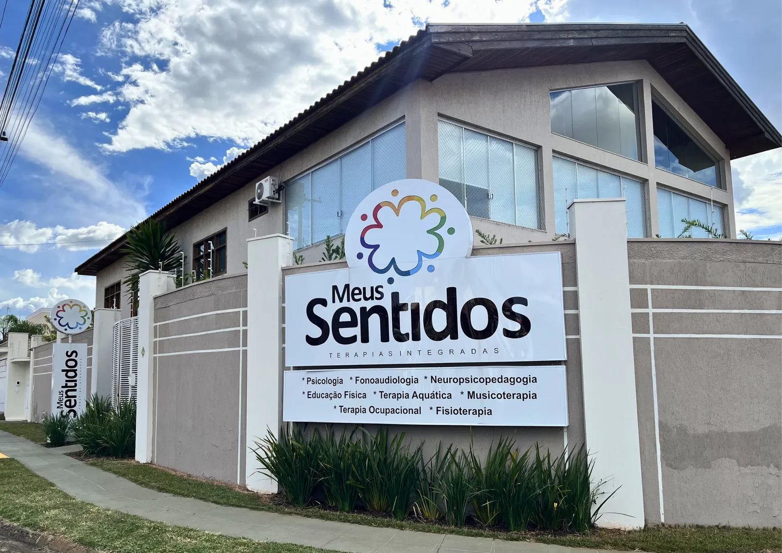 Fachada da Clínica Meus Sentidos, com a placa da clínica e o jardim na entrada.