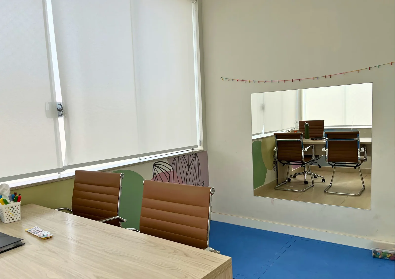 Sala de atendimento com mesa, cadeiras e piso azul.