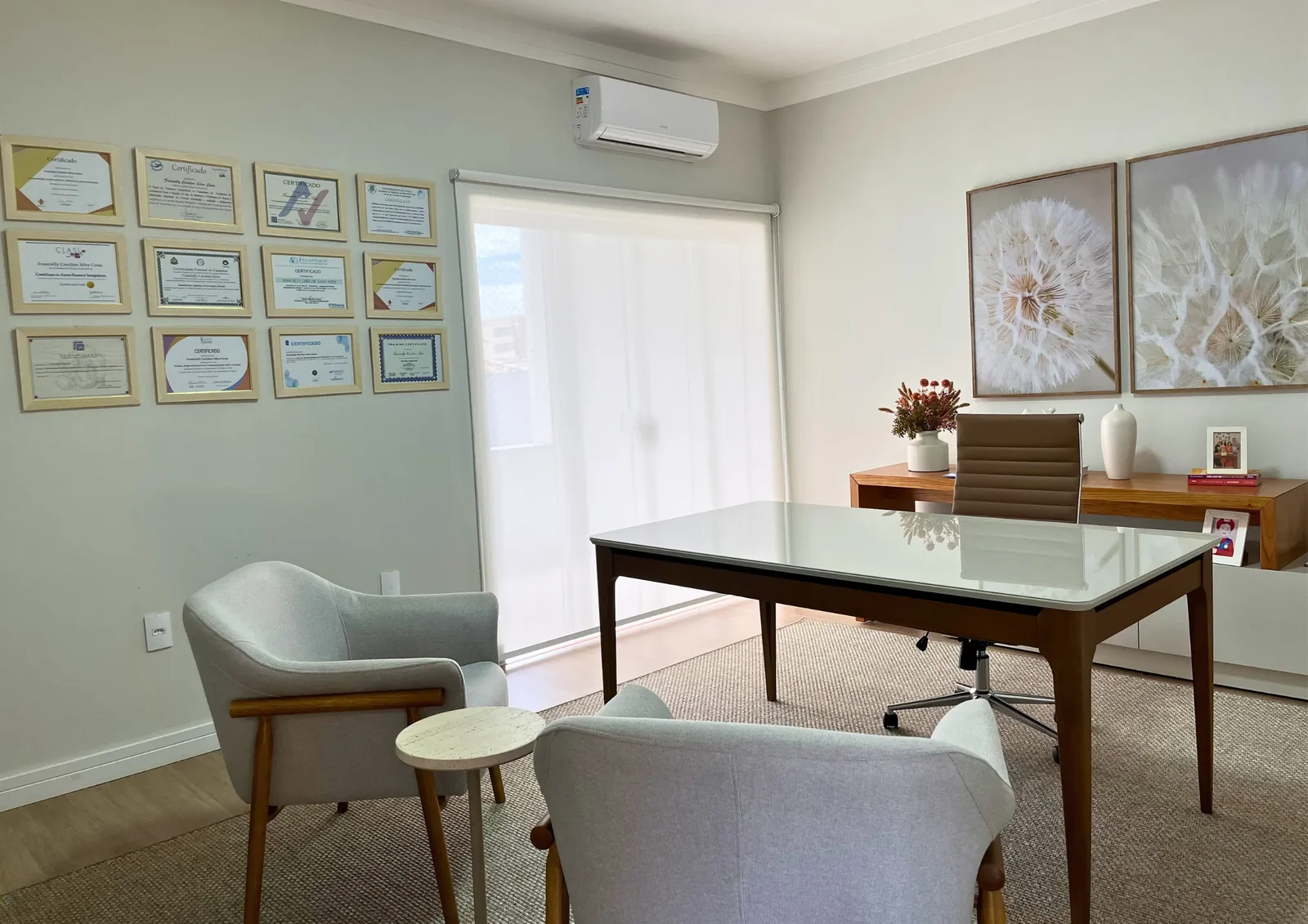 Sala de reunião com mesa de madeira, poltronas e quadros na parede.
