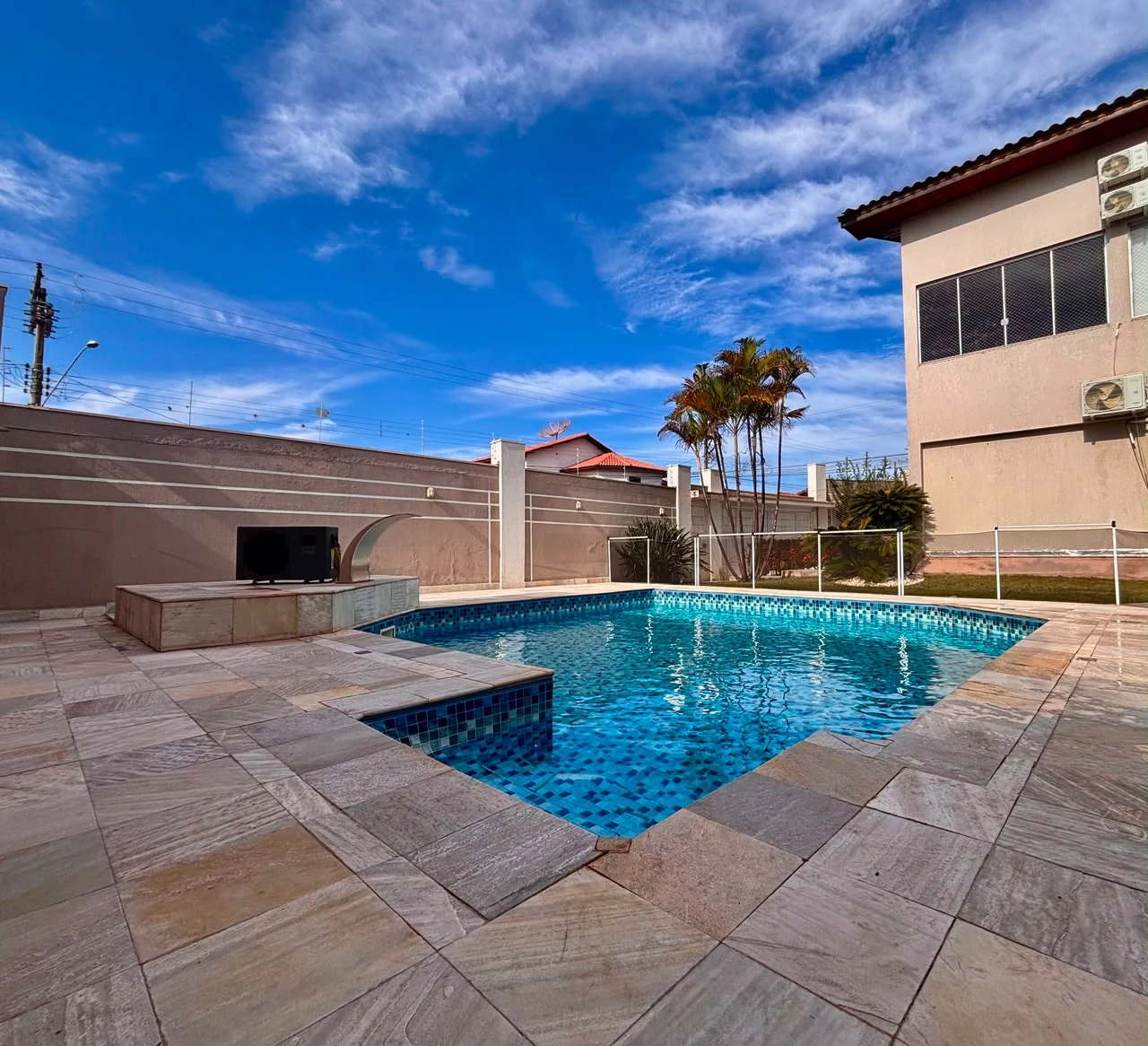 Área da piscina, com deck em pedra e cerca de proteção.